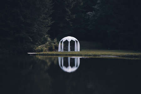White wedding pavilion altar next to a small lake