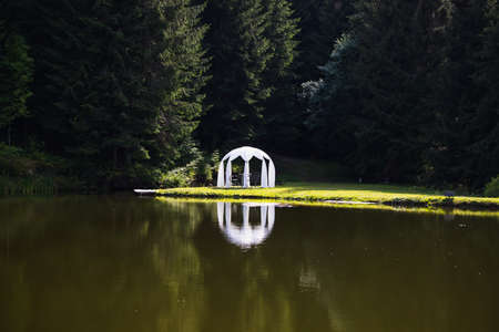 White wedding pavilion altar next to a small lakeの写真素材