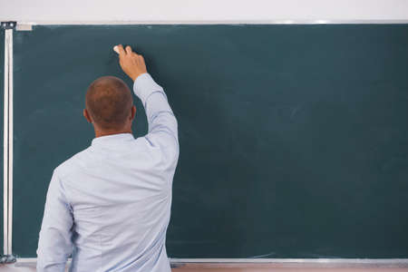 Teacher or student writing on blackboard in school classroom.の写真素材
