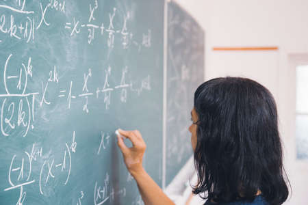 Teacher or student writing on blackboard during math lesson in school classroom.の写真素材