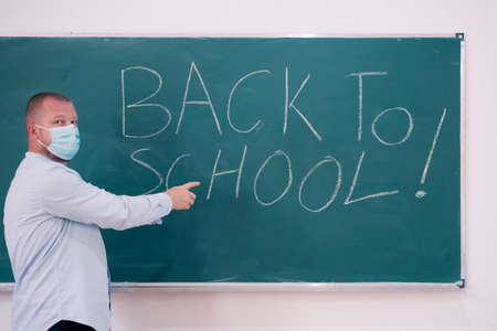 Back to school concept: teacher giving books to her studens in the classroom at the begining of the new school season.の写真素材