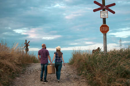 Young couple holding vintage suitcase at the railway station platformの写真素材
