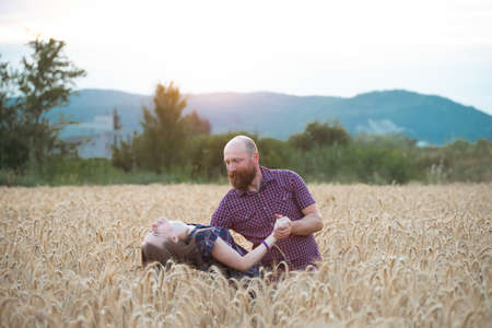 Couple having fun and enjoying relaxation in a wheat field. The concept of youth, love and...