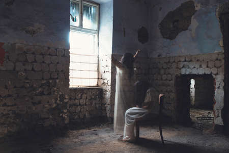 Ghost in abandoned, haunted house. Horror scene of scary spirit of a woman, halloween concept.の写真素材