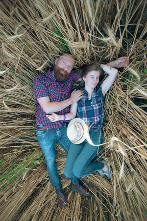 Couple laying and enjoying relaxation in a wheat field. The concept of youth, love and lifestyle.の写真素材