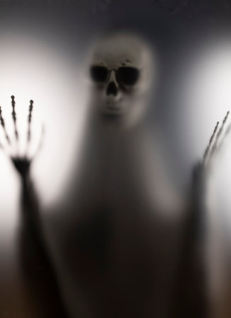 Horror skeleton or grim reaper behind the matte glass. Halloween festival concept.Blurred pictureの写真素材