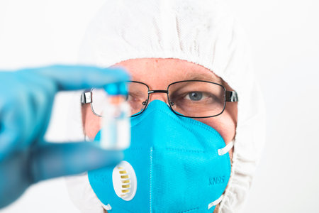 COVID-19 coronavirus vaccine. Vaccination concept. Doctor's hand in blue gloves hold medicine vaccine vial bottle and syringe.の写真素材
