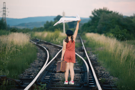 Retro styled photo of little girl with old luggage at the railwaysの写真素材