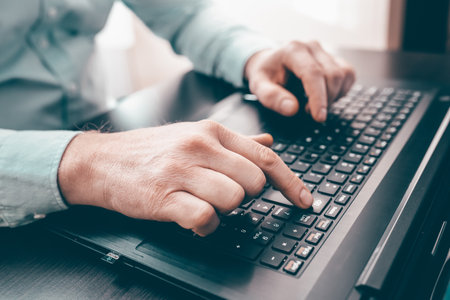 Close up of business man hand working on laptop computer on wooden desk as conceptの写真素材