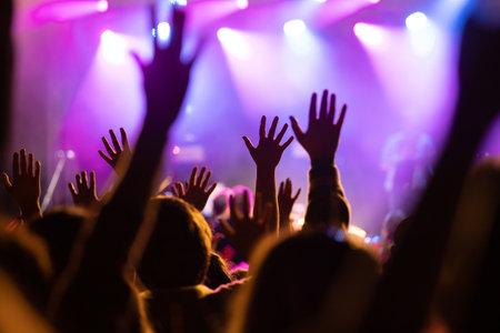 Crowd at concert - Cheering crowd in front of bright colorful stage lightsの写真素材