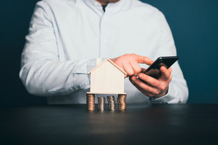 Businessman with house model and piles of coins.Realtor, mortgage, saving money, home loan concept.の写真素材