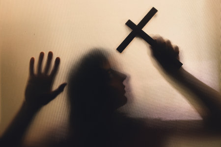 Horror ghost woman holding a cross behind the matte glass. Halloween festival concept.の写真素材