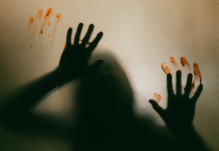 Horror ghost woman with blooded hands behind the matte glass. Halloween festival concept.の写真素材