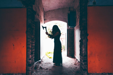Ghost in abandoned, haunted house. Horror scene of spooky silhouette holding old axe, halloween concept.の写真素材