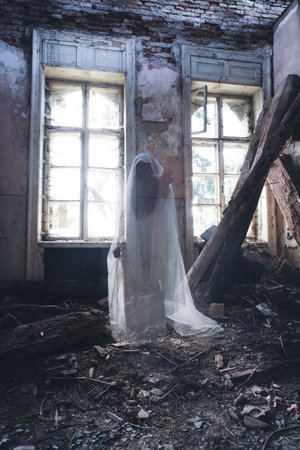 Ghost in abandoned, haunted house. Horror scene of scary spirit of a woman, halloween concept.の写真素材