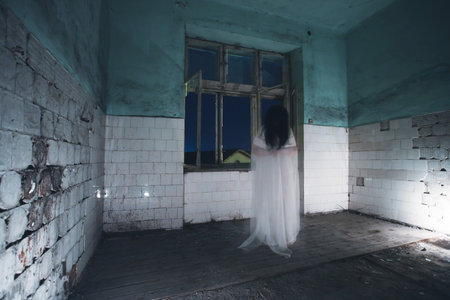 Ghost in abandoned, haunted house. Horror scene of scary spirit of a woman, halloween concept.の写真素材