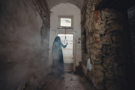 Ghost in abandoned, haunted house. Horror scene of scary spirit of a woman and rope with a noose, halloween concept.の写真素材
