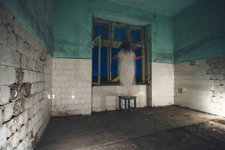 Ghost in abandoned, haunted house. Horror scene of scary spirit of a woman, halloween concept.の写真素材