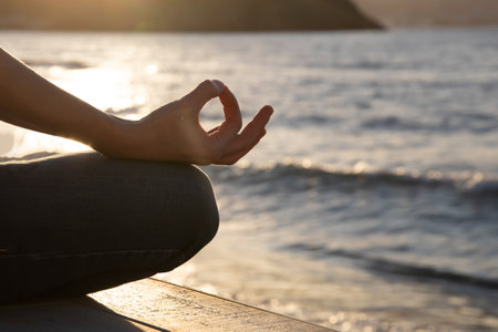 Woman in a yoga pose at sunset at the beach. Mindfulness and mental health concept.の写真素材