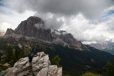 Man trekker with backpack on the hill enjoying picturesque Dolomite Alps view near Cinque Torri, Italy. Active people and mountain concept.の写真素材