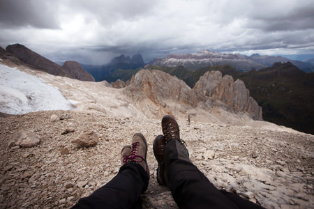 Legs of traveler sitting on a high mountain top in Dolomite mountains, Italy. Concept of freedom,...