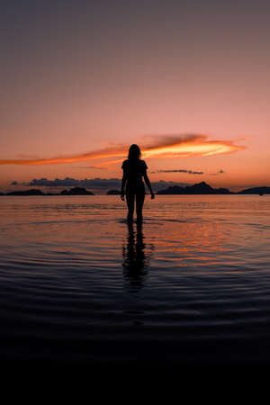 Silhouette of a girl at sunset in El Nido beach.