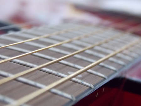 Focus on the golden strings of a red guitar