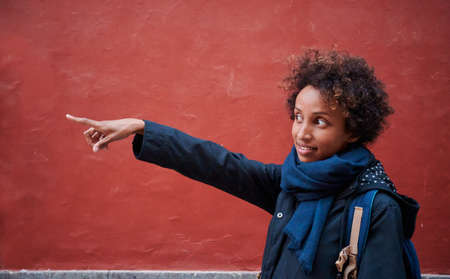 A black woman pointing with her hand on a red wallの写真素材