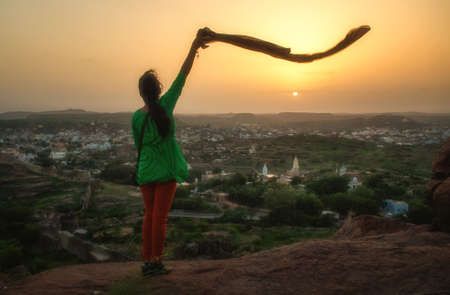 An Indian girl waves her scarf at the sunset over Jodhpur.の写真素材