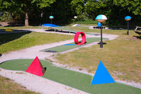 Mini golf, crazy golf course play with red and blue obstacles on a warm sunny dayの写真素材