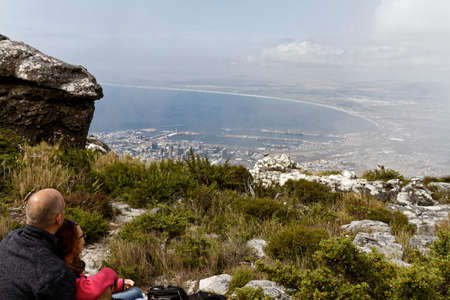 CAPE TOWN - NOV 12, 2015. Man and woman gazing out upon Cape Town from the a view point on top of Table Mountain. Misty cloudy, touristのeditorial素材