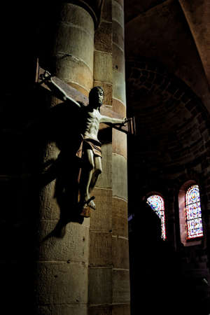 Statue of Jesus Christ crucifixion on a brick wall background in a dark church with stained glass windows. Franceの写真素材