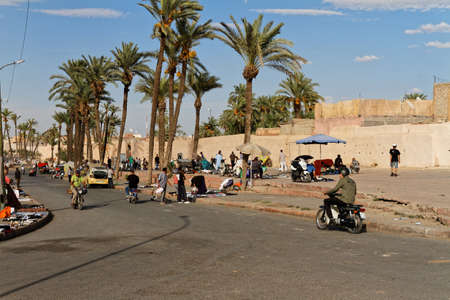 Marrakech, Marocco Okt,7,2018,Street market on sidewalk, blue sky with old city wall and palm trees. People try to sell household and everyday items.の写真素材