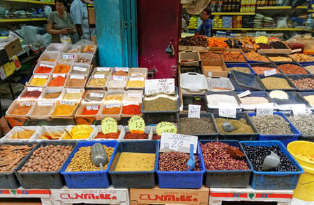 Akko Israel,Oct,9,2016:People buying colorful spices, dried fruit, nuts, seeds and olives at everyday street market. Tags with hebrew names and priceの写真素材