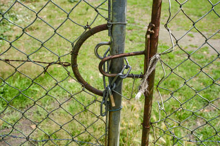 Large fence with wire mesh and barbed wire a chain and a padlock. Grassland, meadow construction site backgroundの写真素材