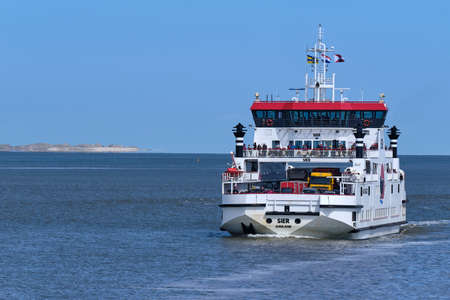 Waddensea, Netherlands-April 26,2021: Car ferry boat with passengers sailing on Wadden Sea from West Frisian island Ameland to Holwerd in Friesland. The island schiermonnikoog in the backgroundのeditorial素材