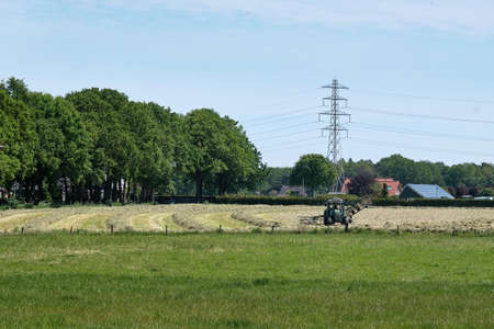 Dronten, the Netherlands June1,2021:Grassland with tractor mower and rake, grass ready to be ensiled.Dutch farmers race against the rain to hay,mow, rake and silage.All farmers are working on the landのeditorial素材