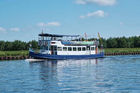 Amersfoort, Hoogland, the Netherlands June 13, 2021, Bicycle boat, ferry eemland on the river Eem with passengers and a dike and blue sky in the background. Boat trip through the Eemvallei and t Gooiのeditorial素材