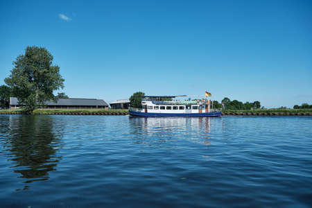 Amersfoort, Hoogland, the Netherlands June 13, 2021, Bicycle boat, ferry eemland on the river Eem with passengers and a dike and blue sky in the background. Boat trip through the Eemvallei and t Gooiのeditorial素材