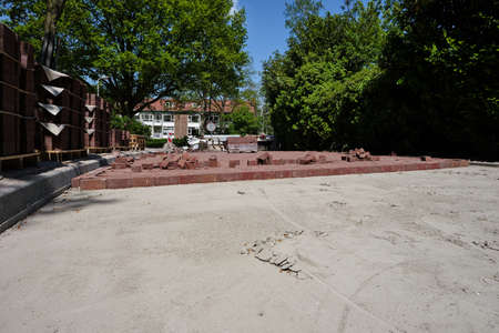 Construction of a cobblestone street. Pile of cobblestones with sand and signage signs, residential block, residential area, houses in the background. The Netherlands 2021の写真素材