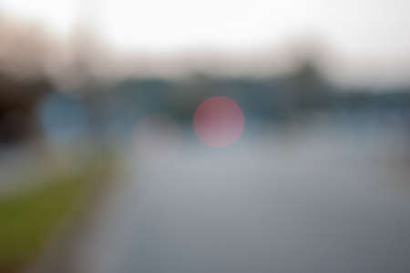 Blurred background. Evening city photo with lights and blur. Blurry photo of the road with traffic lights in the distance and trees at the sides.の写真素材