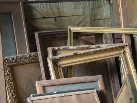 Background of an old gold and brown wooden frames standing against the wall.の写真素材