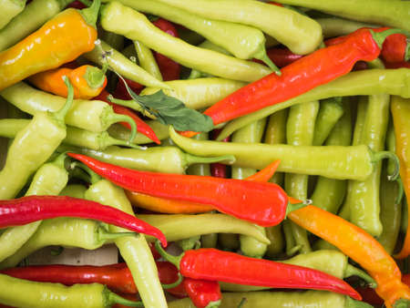 Background of a stacked colourful peppers on sale at the market. Green and red peppers close up.の写真素材
