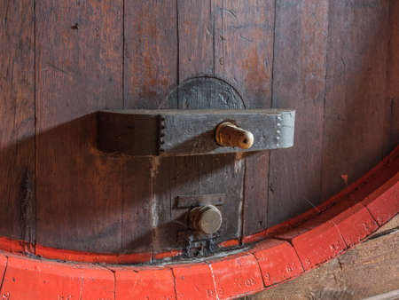Picture of a brown wine barrel stacked in the old cellar of the winery. Background of the wooden...