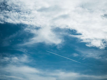 Picture of the blue sky with light clouds and vapor trail. Background of the blue sky with small...