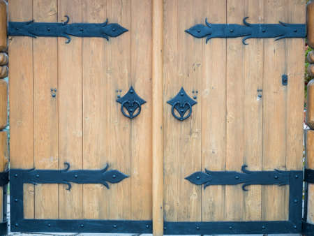 Picture of the double door with blue door handle close up. Background of the bright coloured wooden gate with blue door handle and iron ornament. Texture of a wooden gate close up.の写真素材