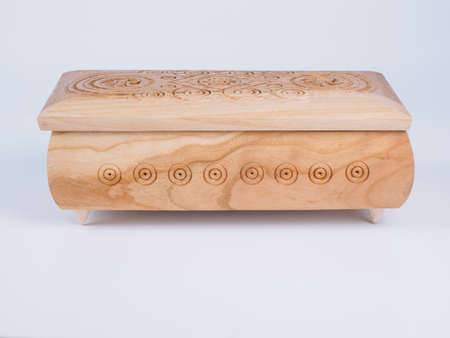 Picture of the carved wooden jewel-box for bijouterie on white background. Carved pattern on a jewel box. Closed box made of light wood. Side view.の写真素材