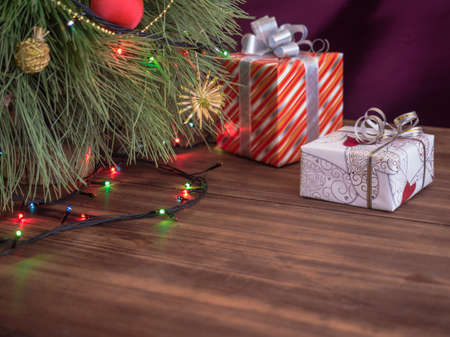 Green Christmas tree decorated with toys and garland with led lights. Boxes with gifts. Christmas present in boxes at wooden table. Green fir tree with toys and gifts under the tree.の写真素材