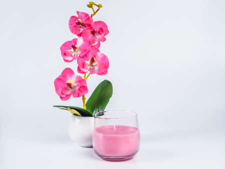 Picture of the orchid with pink candle in a glass on white background. Handmade orchid with candle in a glass close up.の写真素材