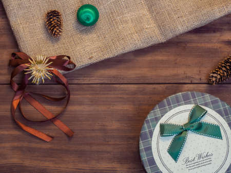 Vintage gift box, fir cones, Christmas toy, ribbon with bow on wood and burlap vintage background,...
